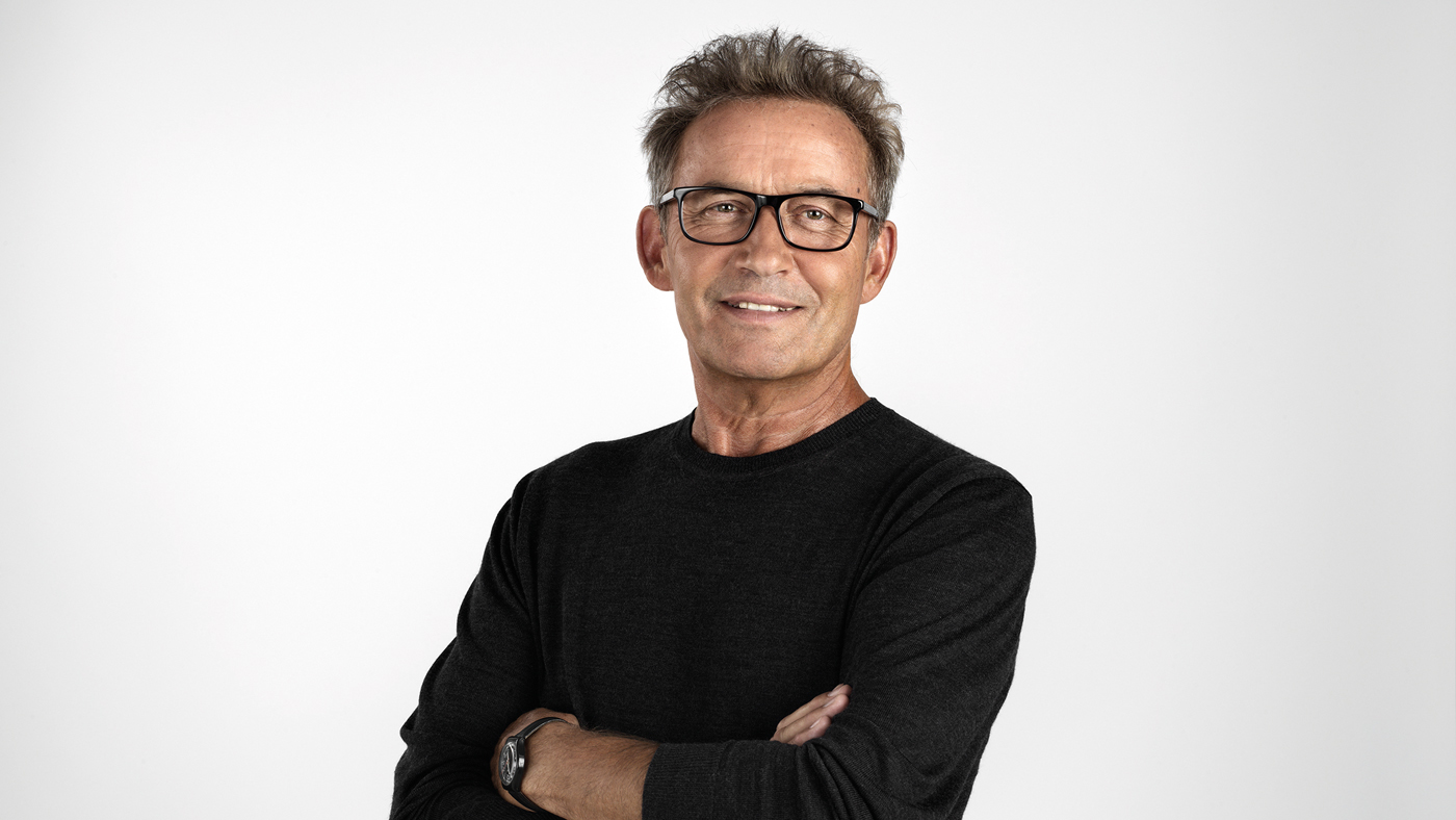 Älterer Mann mit verschränkten Armen lächelt